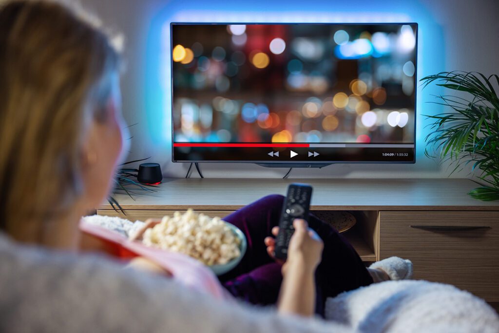 Woman relaxing at home in evening and watching TV.